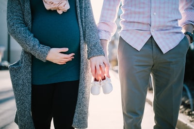 男人站在孕妇抱着婴儿的鞋子白天
